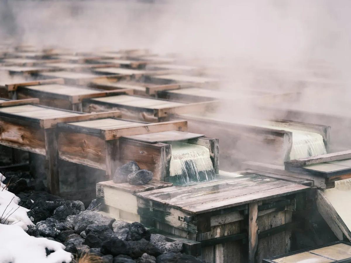L'eau d'une source chaude fume dans ses canaux de bois, en hiver